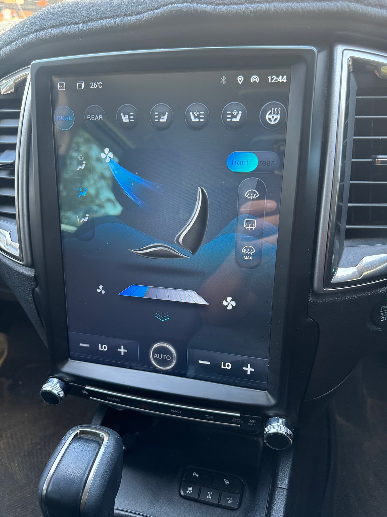 Car dashboard with a touchscreen display showing various icons and settings.